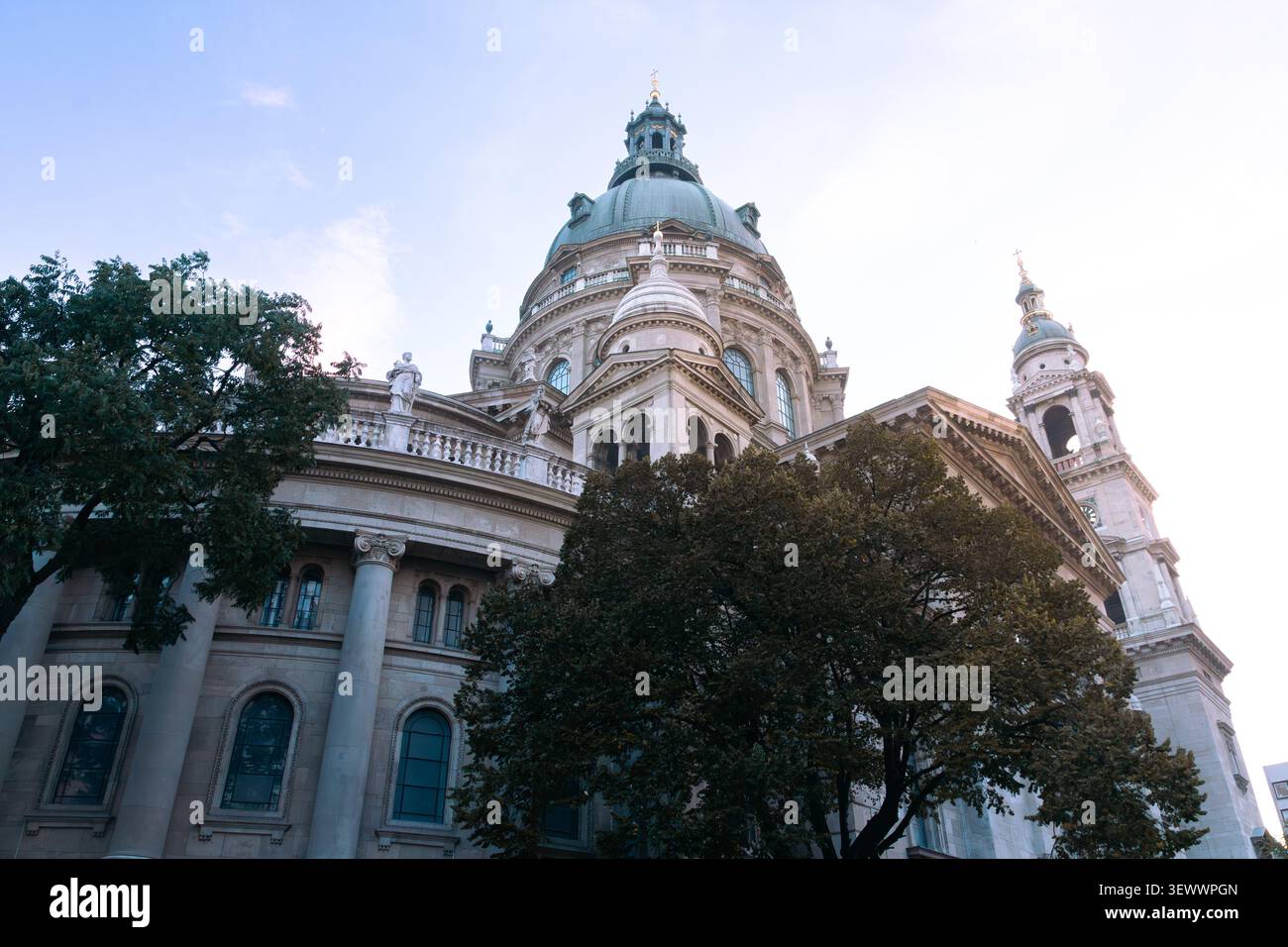 Basilica di Santo Stefano che mostra i suoi dettagli architettonici neoclassici, la cupola dominante e l'intreccio di pietra complessa contro un cielo luminoso, enfatizzando l'eredità culturale e religiosa di Budapest Foto Stock