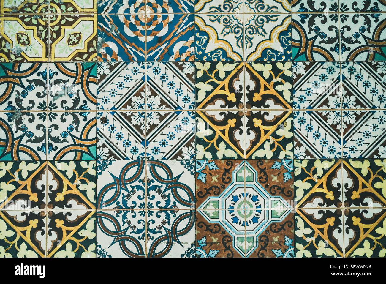 Piastrelle in ceramica a motivi vintage che formano una superficie vibrante e decorativa, presentando un ricco arazzo di disegni tradizionali e forme geometriche con una finitura antica e consumata Foto Stock