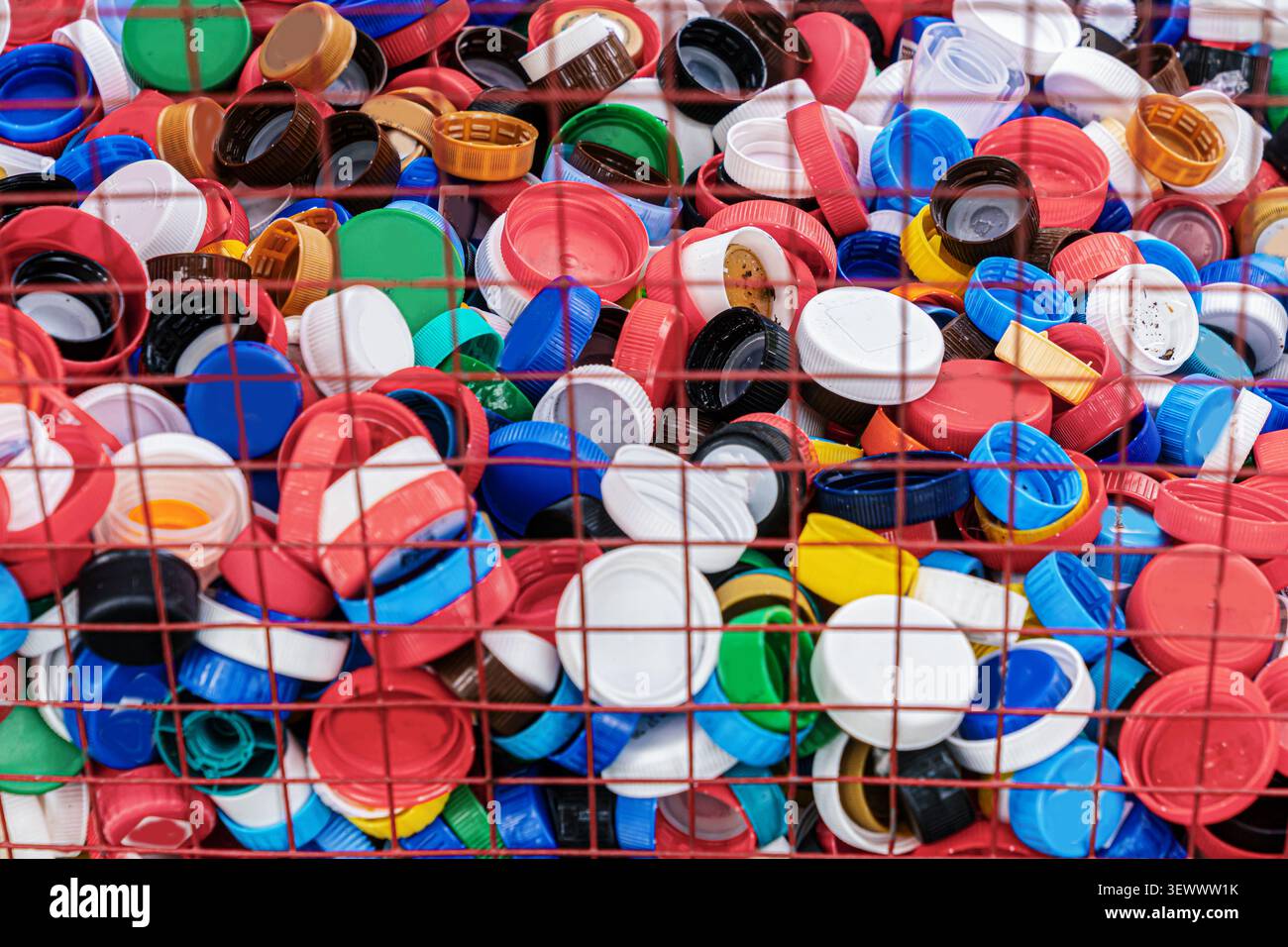 Tappi colorati per bottiglie in plastica raccolti in un contenitore di riciclaggio. Concetto di riciclaggio di materie plastiche, smistamento dei rifiuti, materiali riutilizzabili, riduzione della plastica pol Foto Stock