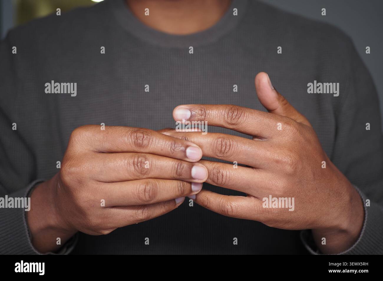un giovane uomo le mani si avvicinano, somiglianti a gesti associati a dolore o dolori articolari Foto Stock
