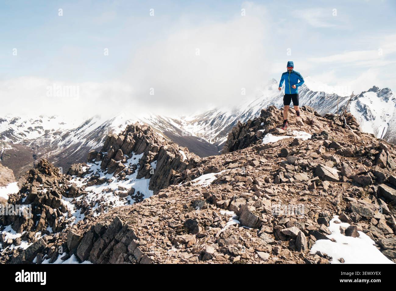 Atleta maschile che corre su un crinale innevato Foto Stock
