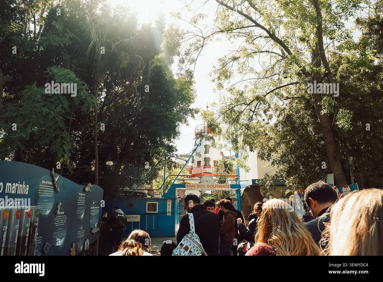 27 febbraio 2024, Portogallo, Lisbona - Zoo. Jardim Zoologico. La gente aspetta in fila alla baia dei delfini. L'area circostante gli alberi, le strutture colorate sono visibili Foto Stock