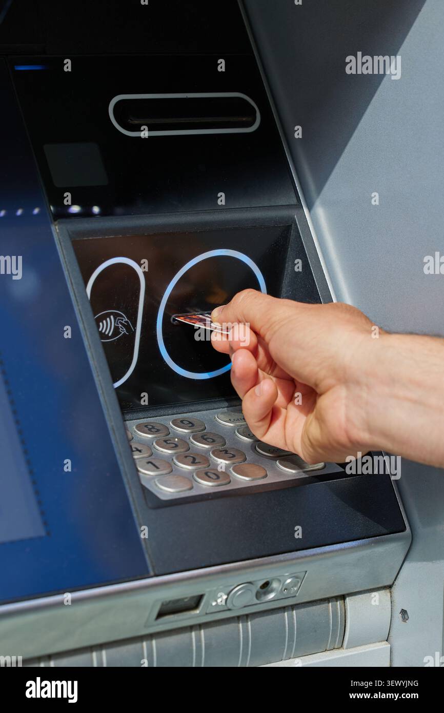 La mano umana inserisce una scheda di plastica in un bancomat Foto Stock