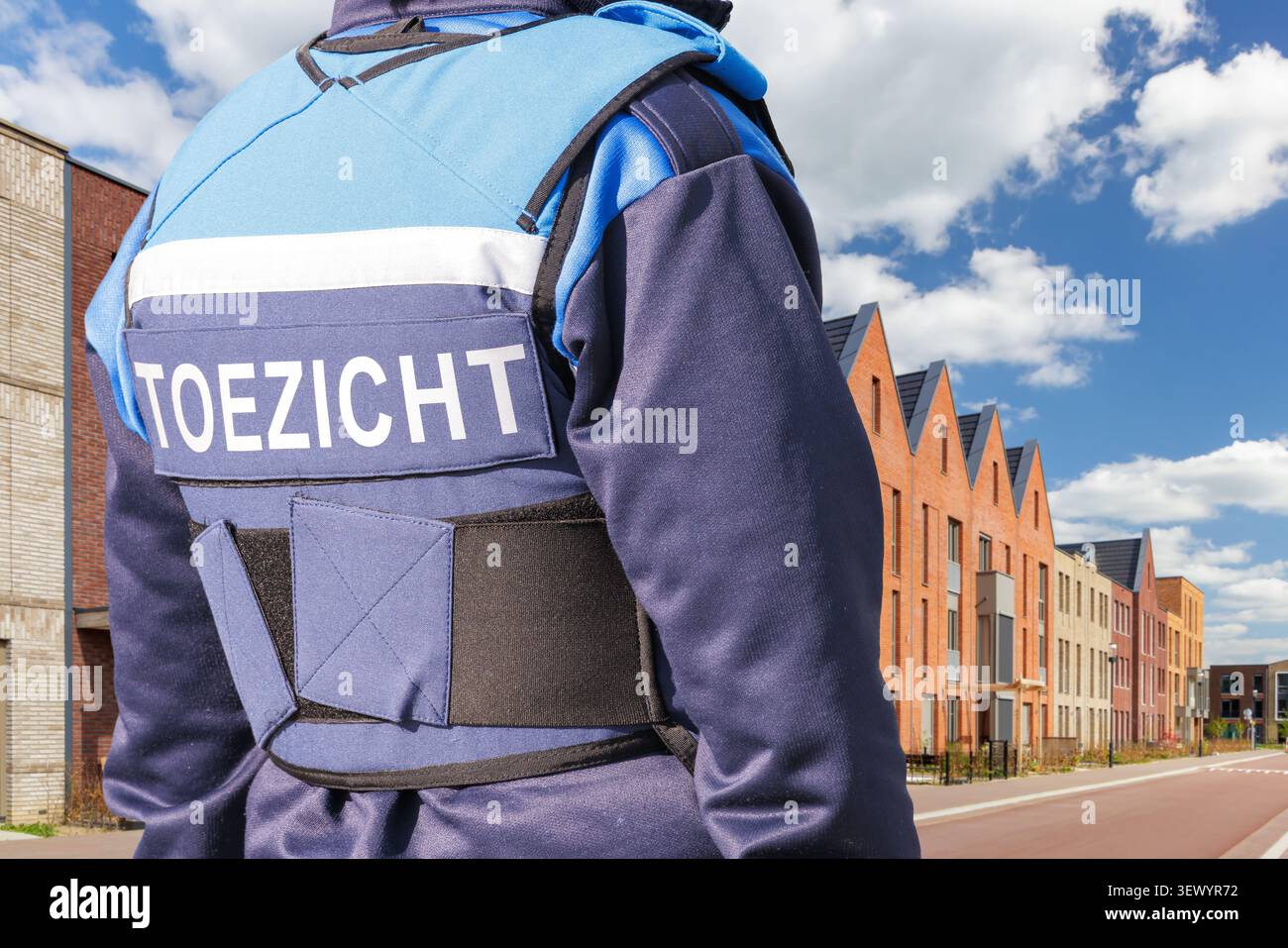Funzionario pubblico municipale con testo in uniforme olandese "sorveglianza" che guarda una strada della città Foto Stock