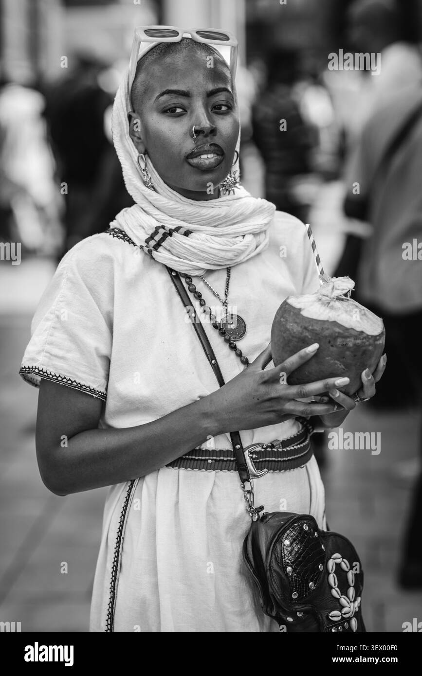 Immagine in bianco e nero dell'artista musicale Teshay Makeda, l'imperatrice del roots soul, che gusta una noce di cocco al Windrush Big Caribbean Lunch 2026. Foto Stock