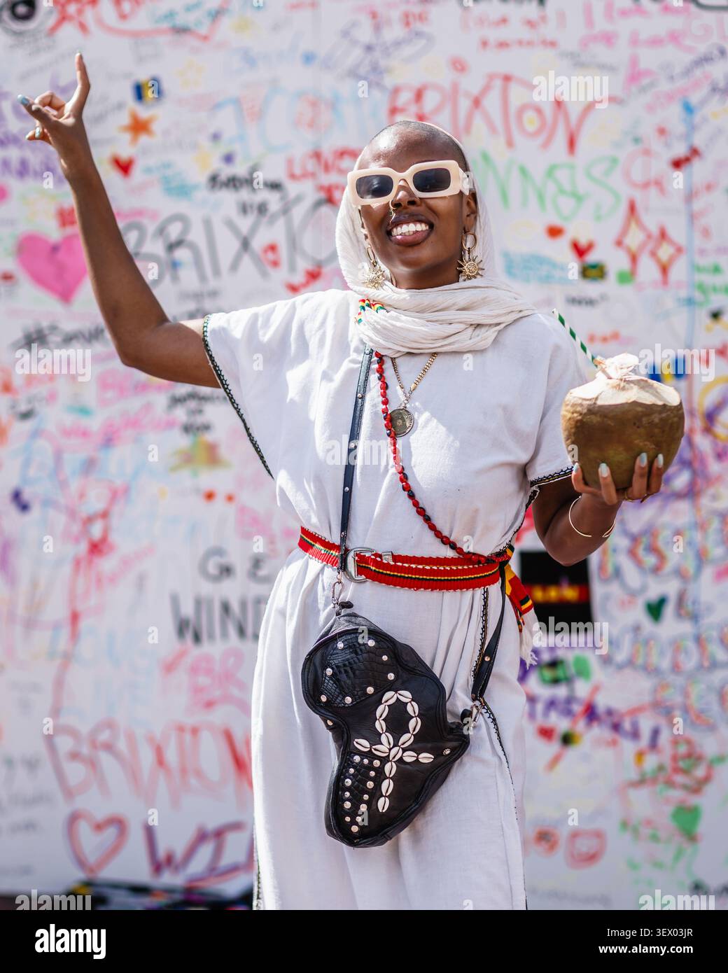 L'artista musicale Teshay Makeda si gode il succo di cocco al Windrush Big Caribbean Lunch 2026 a Brixton. Foto Stock