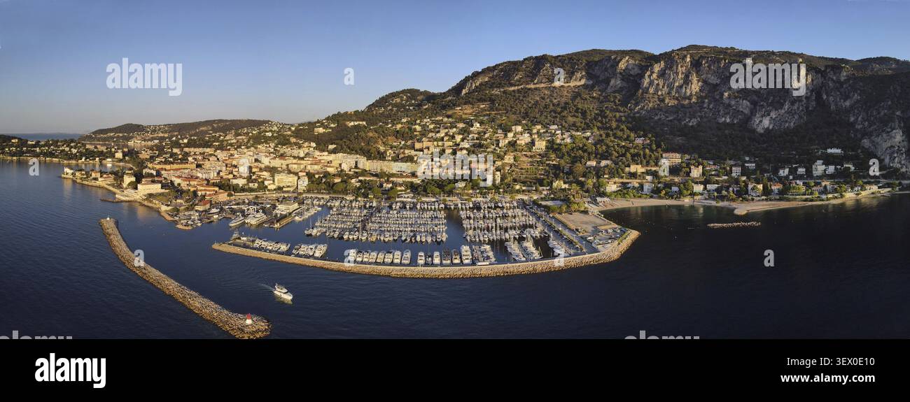 Vista aerea di una città costiera con un porticciolo pieno di barche, circondata da montagne e acque blu calme, Marina. Beaulieu-sur-Mer, Francia Foto Stock