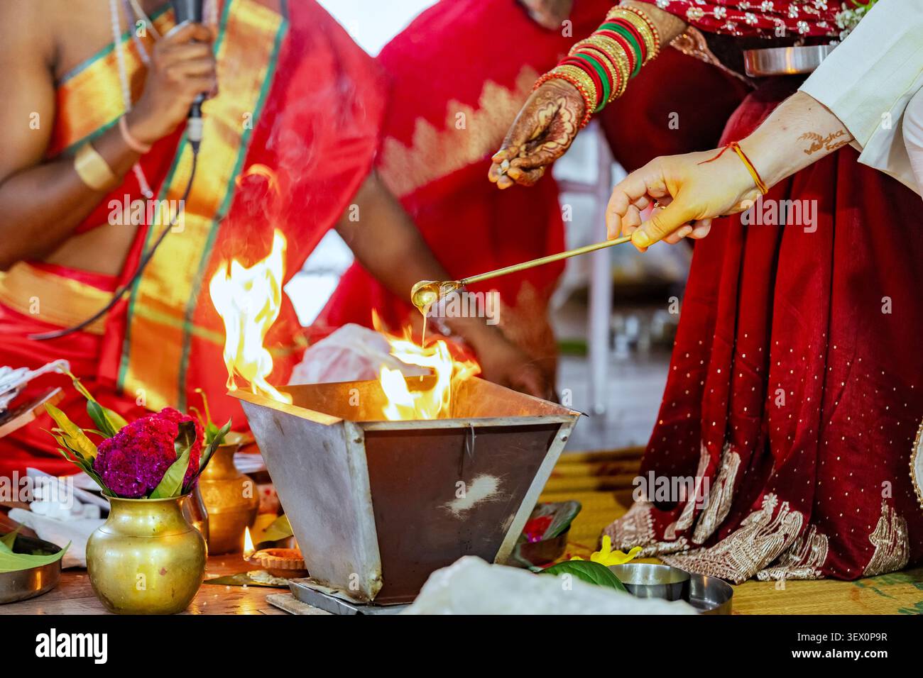 Cerimonia di nozze indù con rituale sacro del fuoco e offerte in corso Foto Stock