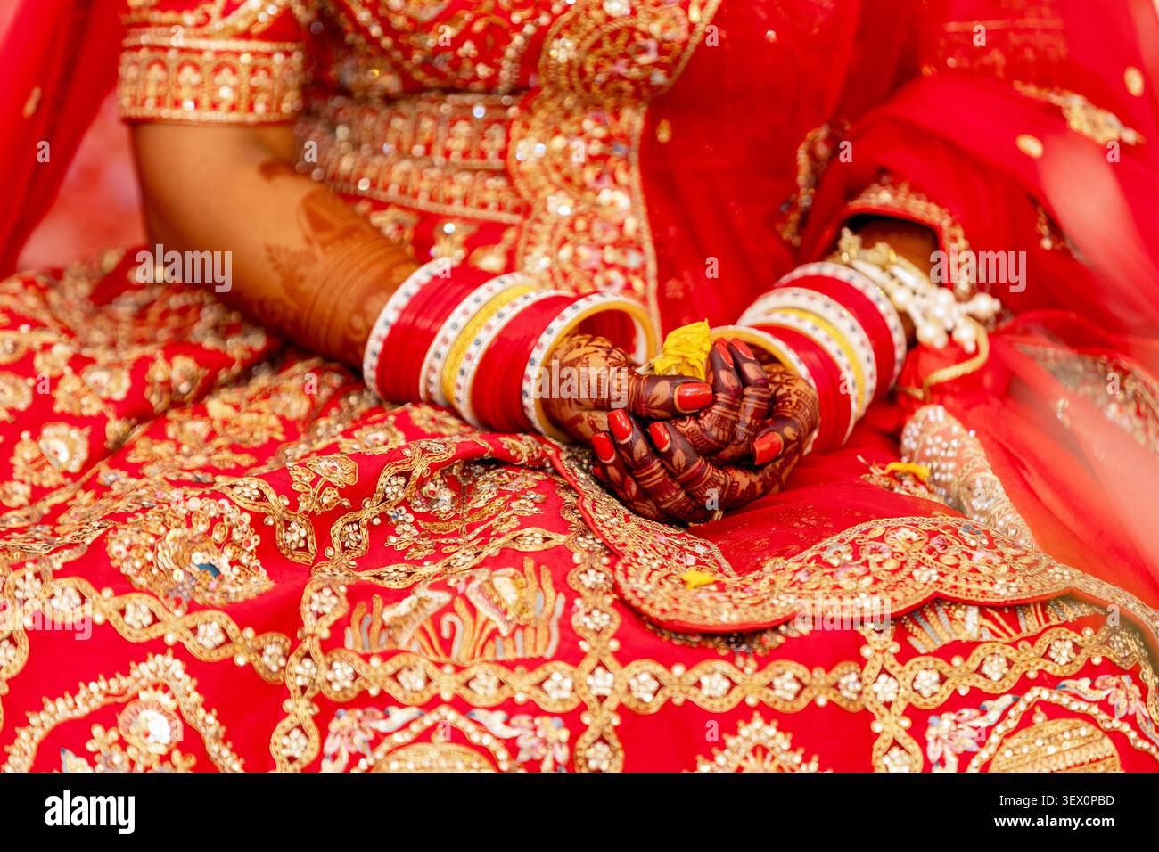 Intricati dettagli delle mani di una sposa adornate con henné e bracciali durante una cerimonia tradizionale Foto Stock