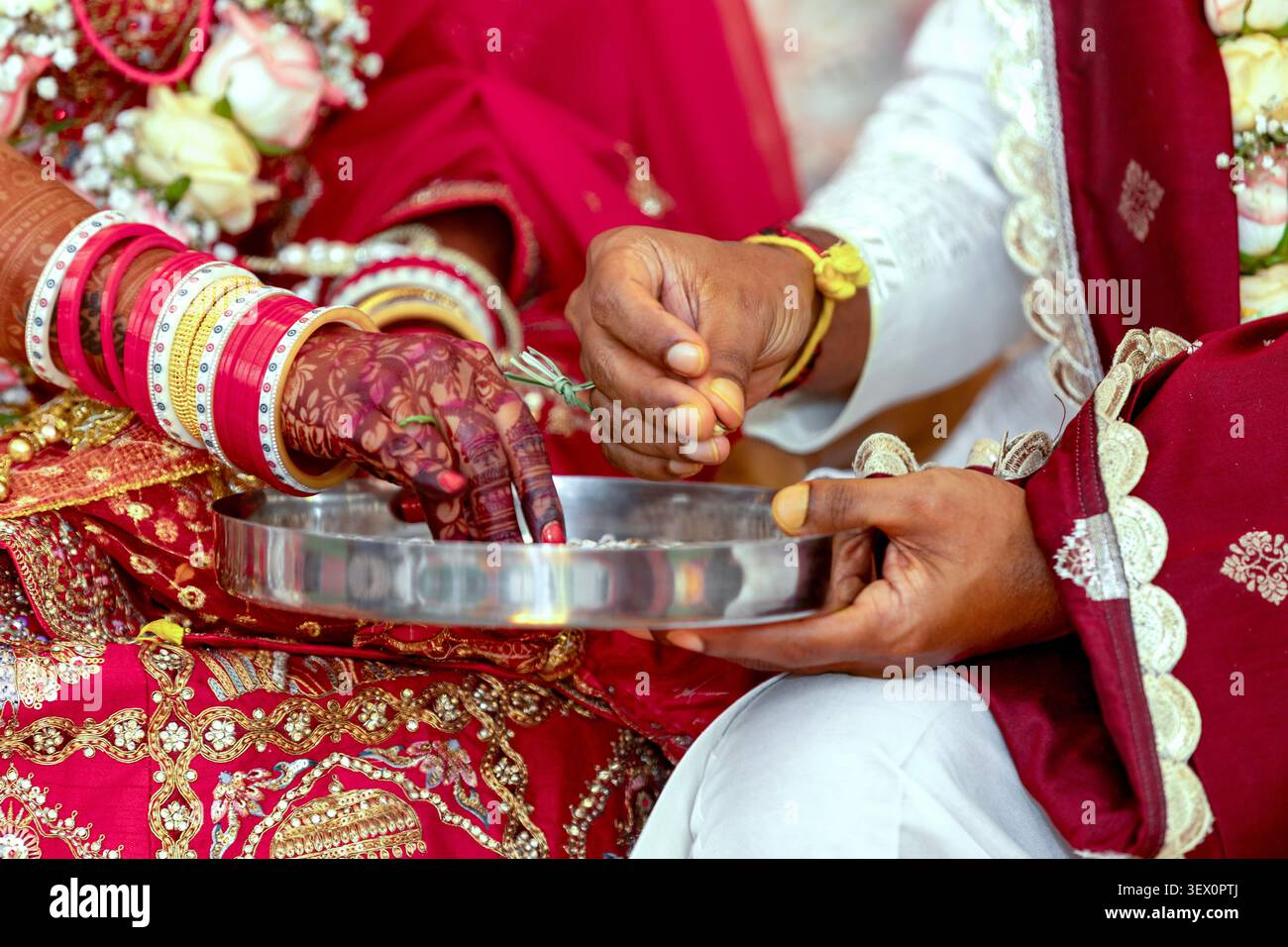 La sposa e lo sposo indiani eseguono rituali nuziali con riso e braccialetti Foto Stock