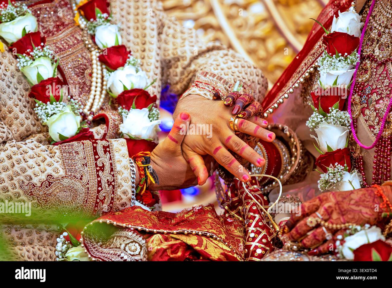 Intimo momento di una sposa e uno sposo che si tengono per mano durante una tradizionale cerimonia di nozze indiana Foto Stock