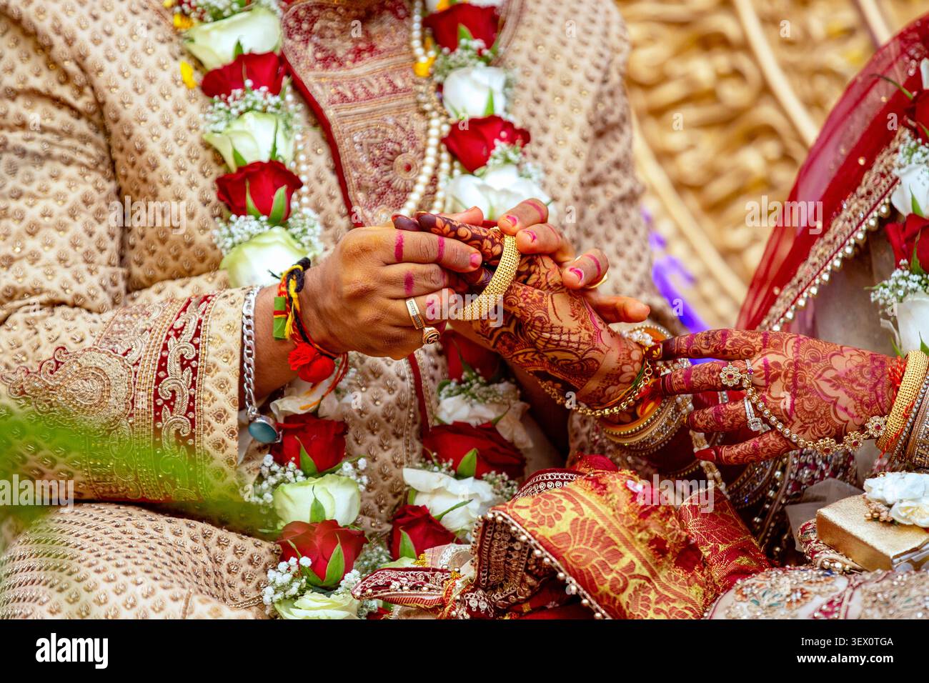 Primo piano delle mani di una sposa e di uno sposo adornate con henné e gioielli durante un tradizionale rituale di nozze indiano Foto Stock