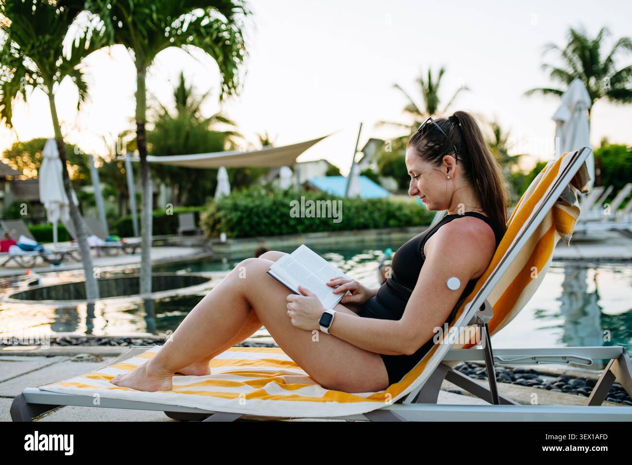 Vivere bene con il diabete mentre si legge in piscina durante le vacanze estive. Foto Stock