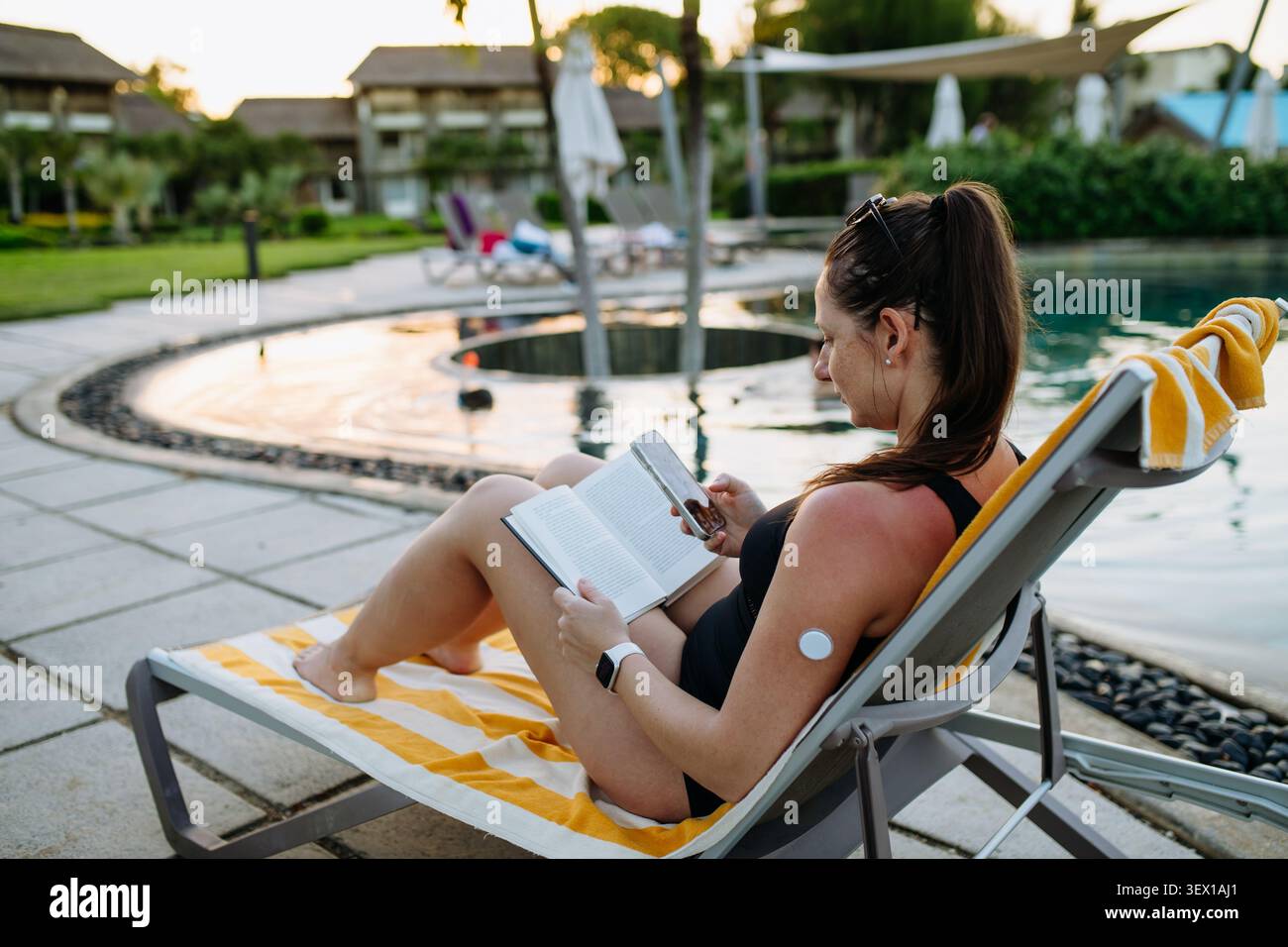 Donna diabetica in vacanza in piscina con sensore per il monitoraggio continuo del glucosio. Foto Stock