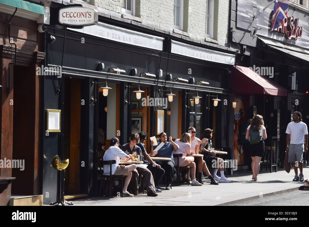 Londra, Inghilterra, Regno Unito. 29 giugno 2026. Le persone si siedono fuori dal Cecconi's Pizza Bar in Old Compton Street a Soho, mentre il sindaco di Londra Sadiq Khan pianifica di usare nuovi poteri per ignorare l'opposizione del Westminster Council all'espansione dei ristoranti all'aperto nella zona. A partire dal 2027 entrerà in vigore un'espansione dei ristoranti in cui è consentito mettere posti a sedere all'esterno durante i mesi caldi. (Credit Image: © Vuk Valcic/ZUMA Press Wire) SOLO PER USO EDITORIALE! Non per USO commerciale! Foto Stock