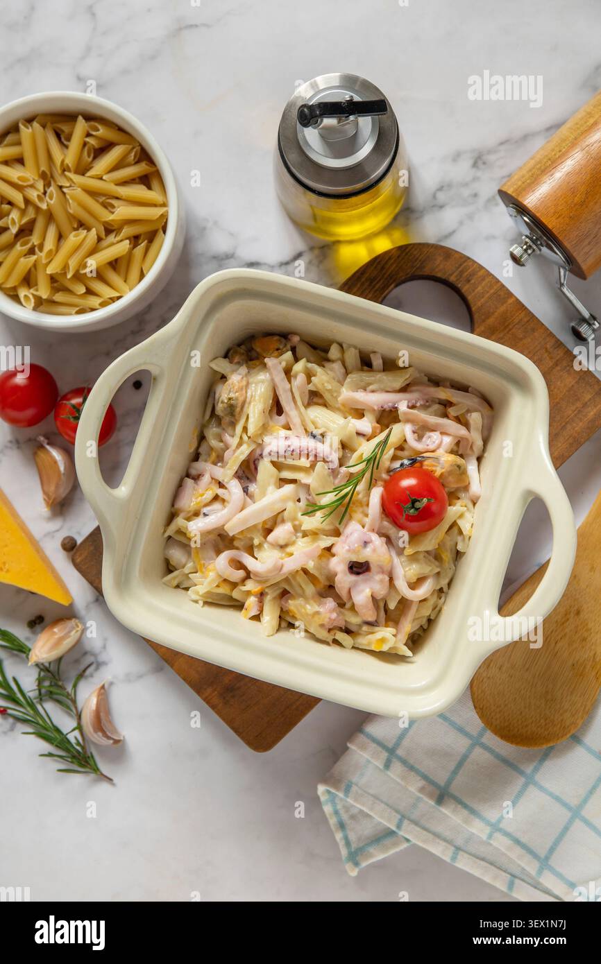 Saporita penne fatte in casa con frutti di mare in salsa cremosa al formaggio su un ripiano in marmo. Sfondo piatto della vista superiore. Copia spazio. Foto Stock