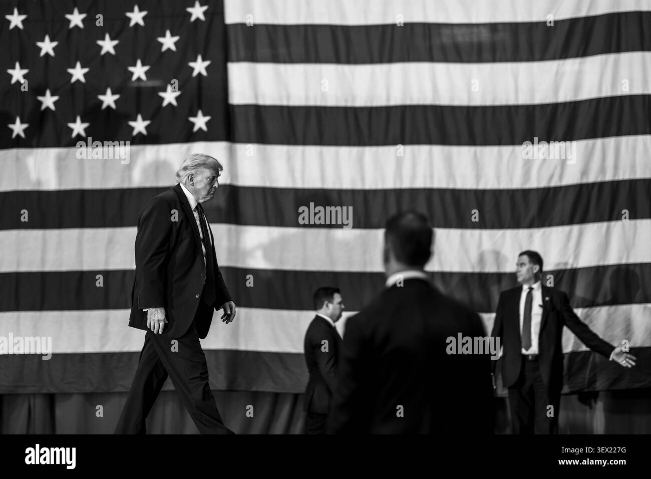 Macungie, Stati Uniti. 23 giugno 2026. Il presidente degli Stati Uniti Donald Trump, esce dal palco davanti a una gigantesca bandiera americana, dopo aver pronunciato osservazioni presso la Mack Trucks Lehigh Valley Operations, 23 giugno 2026 a Macungie, Pennsylvania. Mack Trucks è interamente di proprietà del gruppo svedese Volvo. Crediti: Molly Riley/White House Photo/Alamy Live News Foto Stock