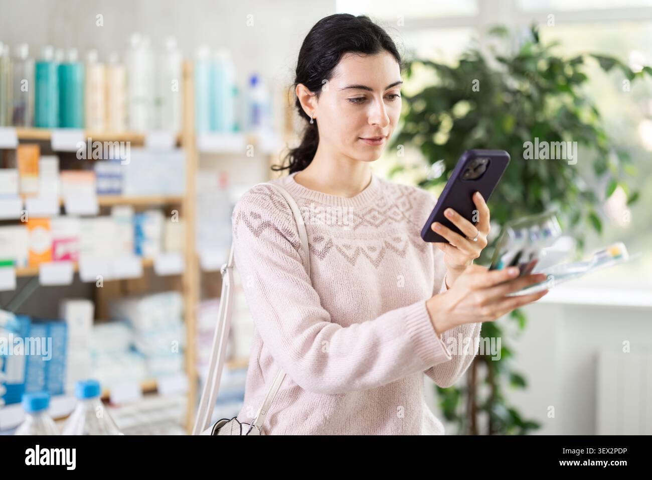 La donna effettua la scansione del codice sull'etichetta dello spazzolino per verificare la data di scadenza Foto Stock
