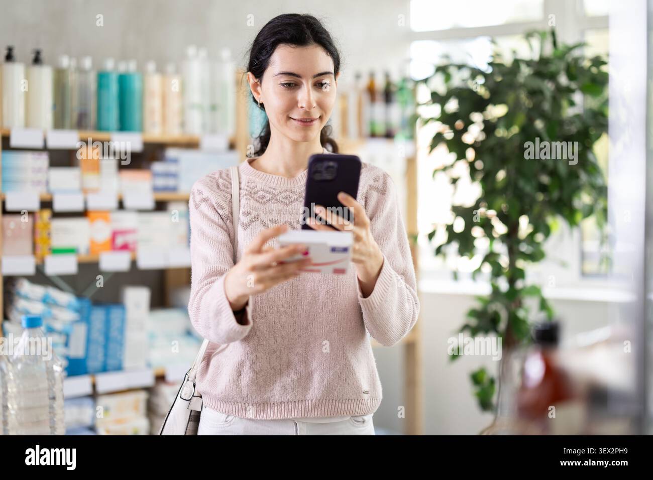 Ragazza in abiti autunnali scansiona il codice sulla confezione di pillole di paracetamolo per controllare la data di scadenza Foto Stock