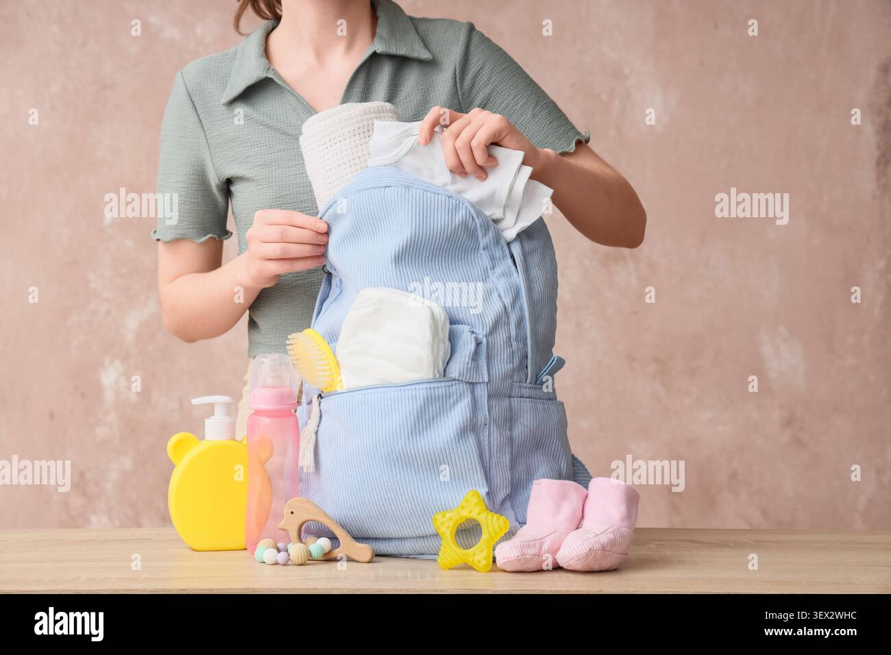 Donna che confeziona gli indispensabili per il bambino in una borsa blu per pannolini Foto Stock