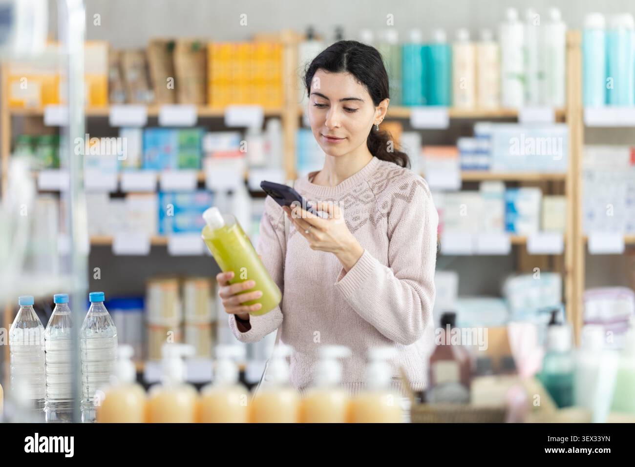 Ragazza in abiti autunnali scansione codice su shampoo medicinale per controllare la data di scadenza Foto Stock