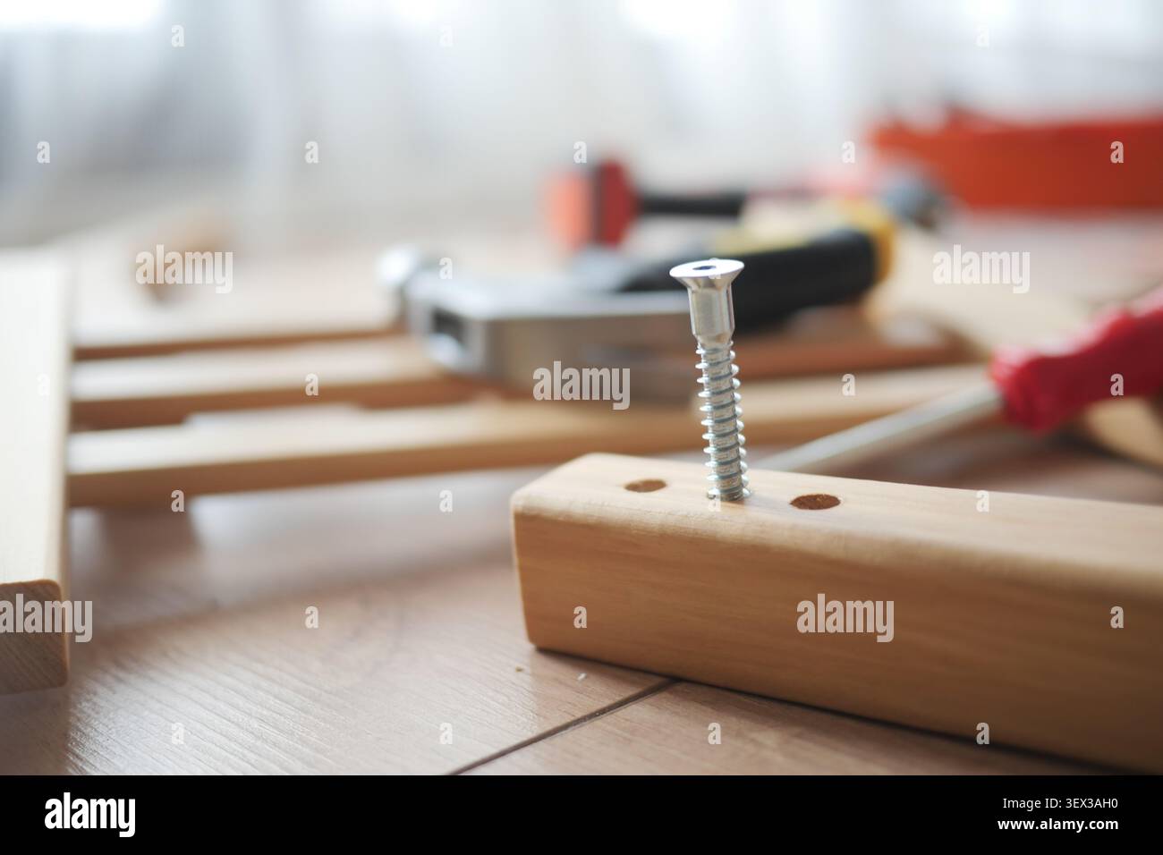 Attrezzi e una vite disposti su una superficie di lavoro Foto Stock