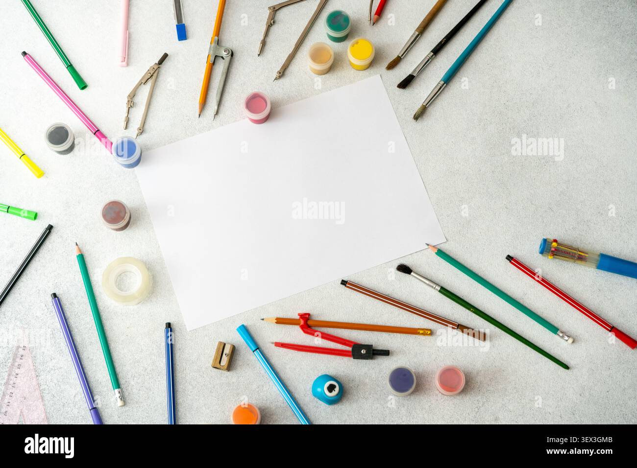 Scrivania Art Workspace con foglio bianco vuoto, matite colorate, pennelli e strumenti di disegno. Tabella di visualizzazione superiore dello sfondo dello studio scolastico Foto Stock