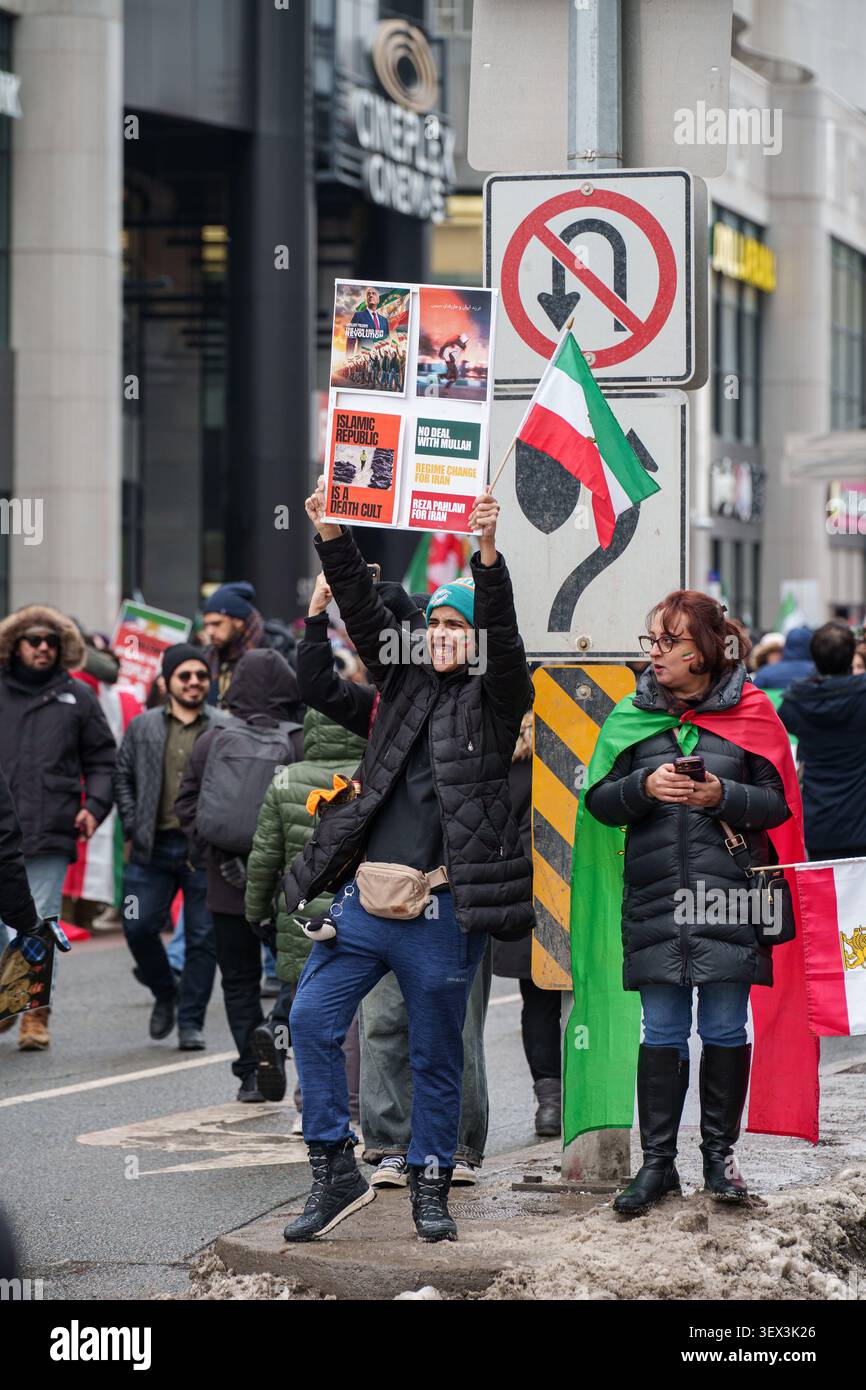 Toronto, Ontario - 14 febbraio 2026: Manifestanti con segni e bandiere al raduno della diaspora iraniana Foto Stock