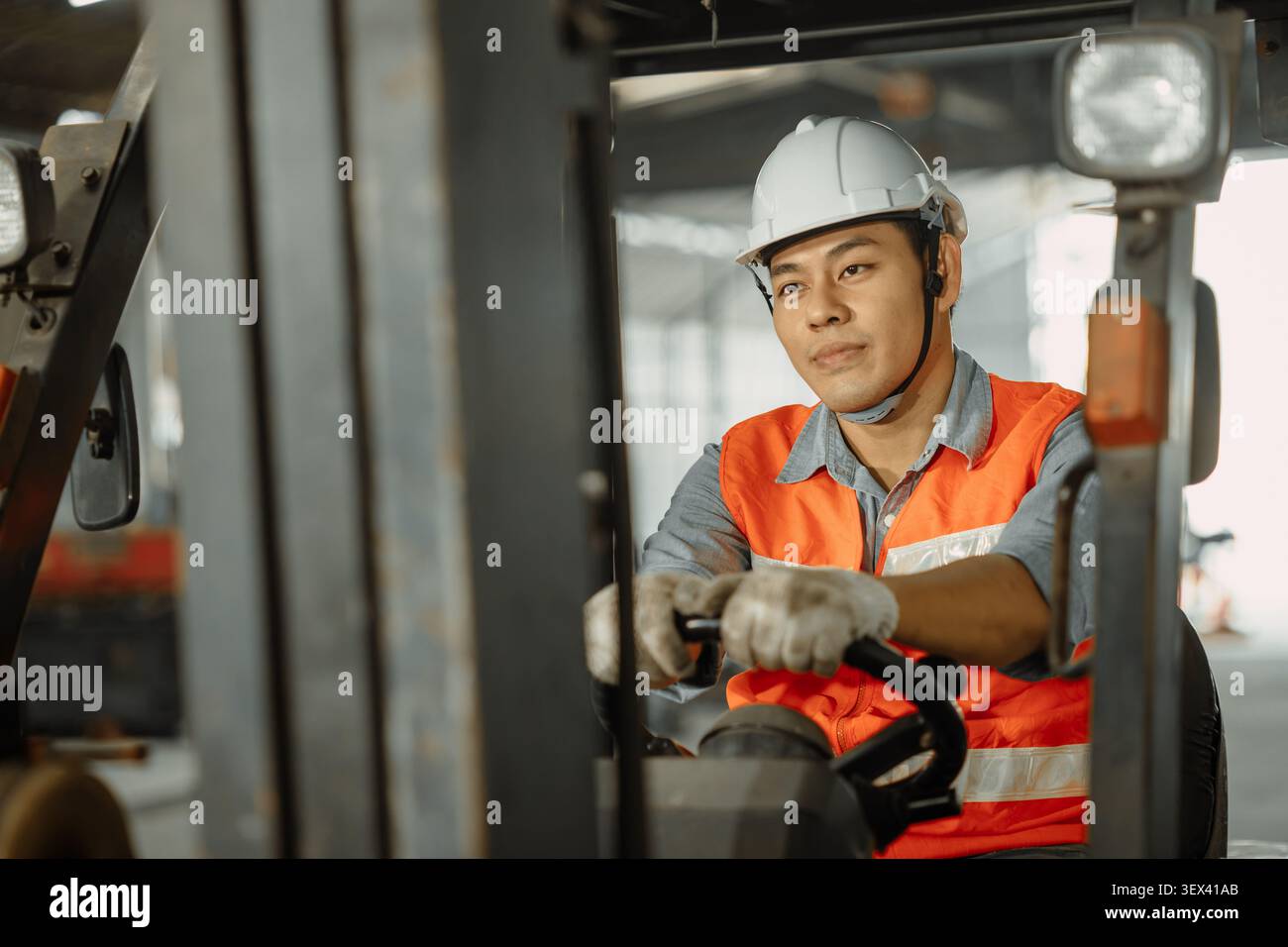 Lavoratore maschio asiatico che guida il conducente del carrello elevatore a forche di lavoro felice nell'industria del magazzino della fabbrica dello stabilimento Foto Stock