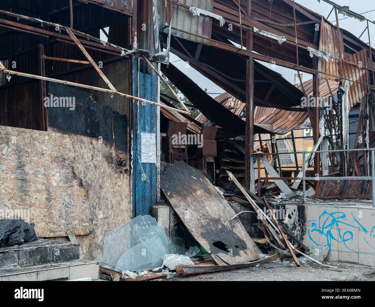 I resti bruciati di una struttura commerciale mostrano travi d'acciaio distrutte e legno compensato rotto, illustrando gravi danni da incendio, decadimento strutturale, A. Foto Stock