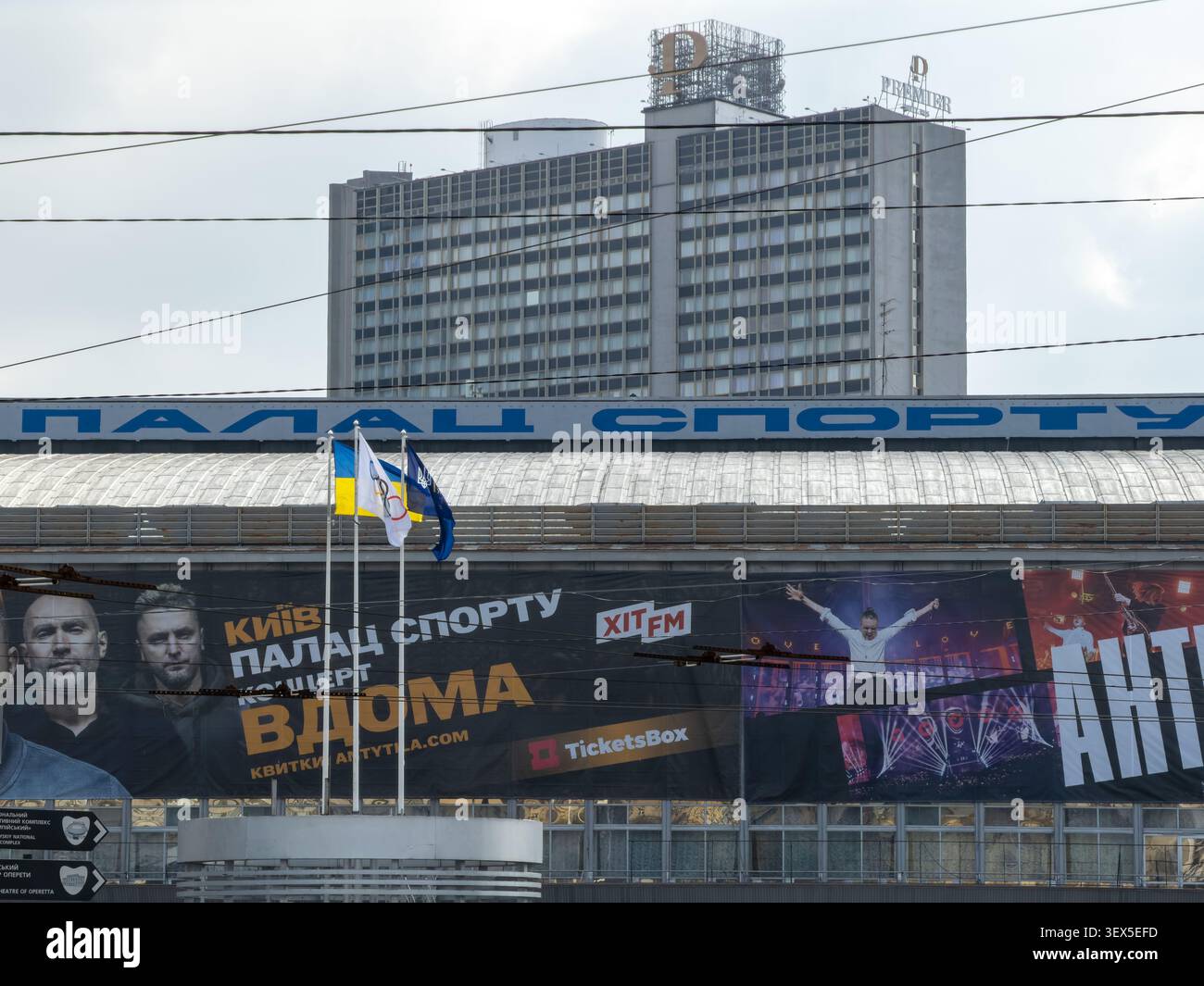 Kiev, Ucraina - 21 marzo 2026: Esterno architettonico dell'arena Palace of Sports che mostra poster e bandiere degli eventi, ambientato contro un lontano Premier H alto Foto Stock
