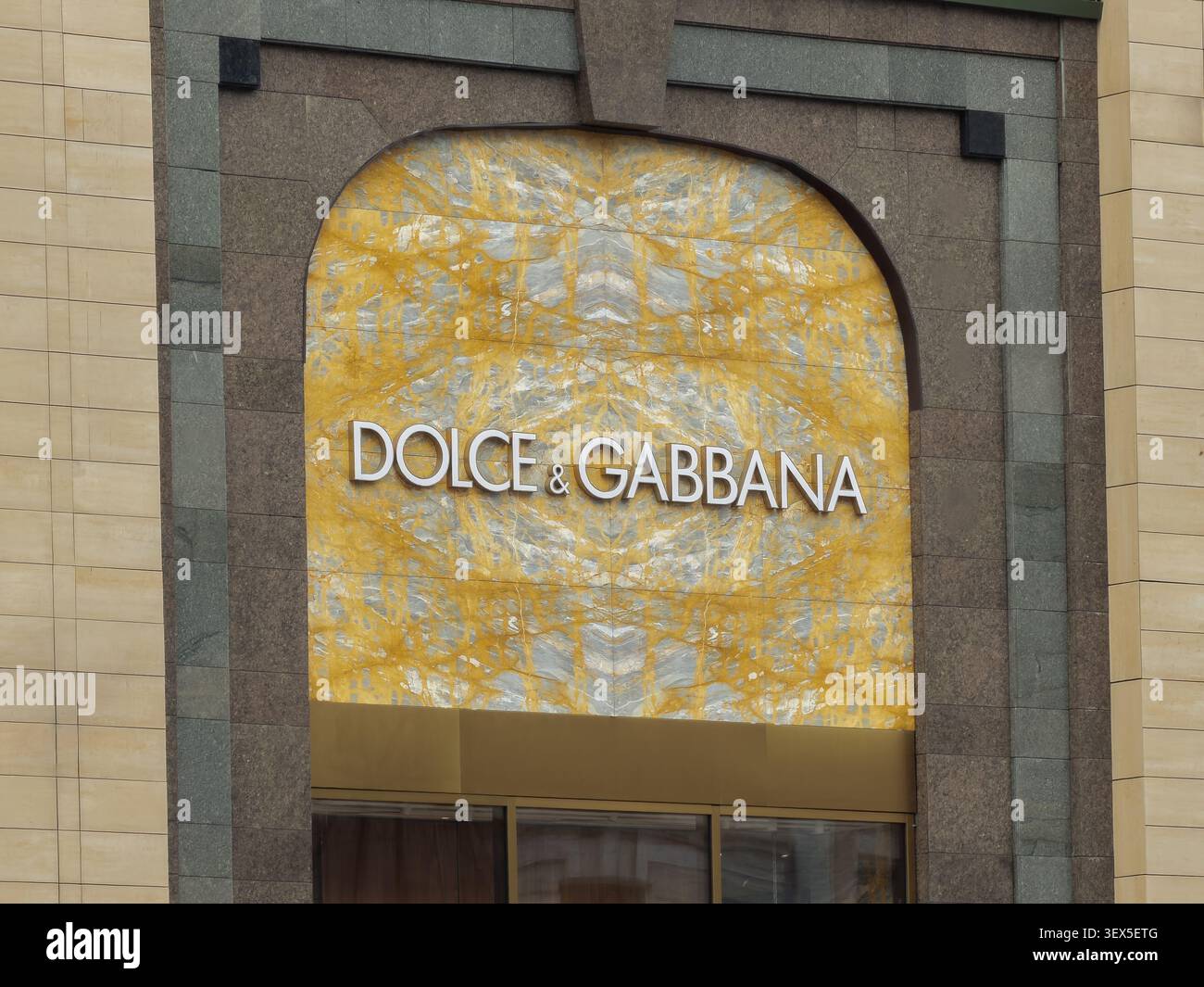 Kiev, Ucraina - 21 marzo 2026: Una targa Dolce e Gabbana esposta su una lastra di marmo giallo lucido incorniciata da archi di granito trasmette prestigio, e. Foto Stock