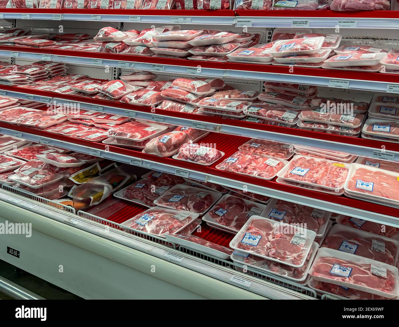 Un espositore refrigerato pieno di varie fette di maiale fresco confezionato in un supermercato. Texas, USA. Foto Stock