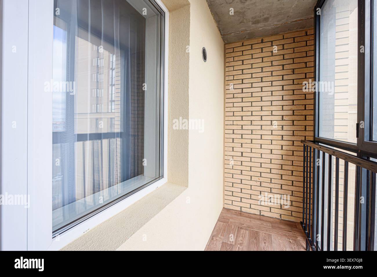 Balcone interno con pareti in mattoni, pareti color crema, pavimento in legno e finestra con cornice bianca. Foto Stock