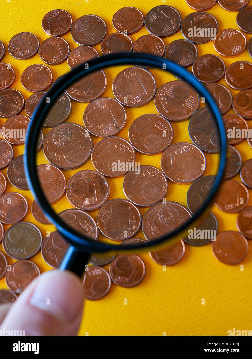 Lente di ingrandimento che mette in evidenza le piccole monete in euro e il loro ruolo nei moderni pagamenti in contanti Foto Stock