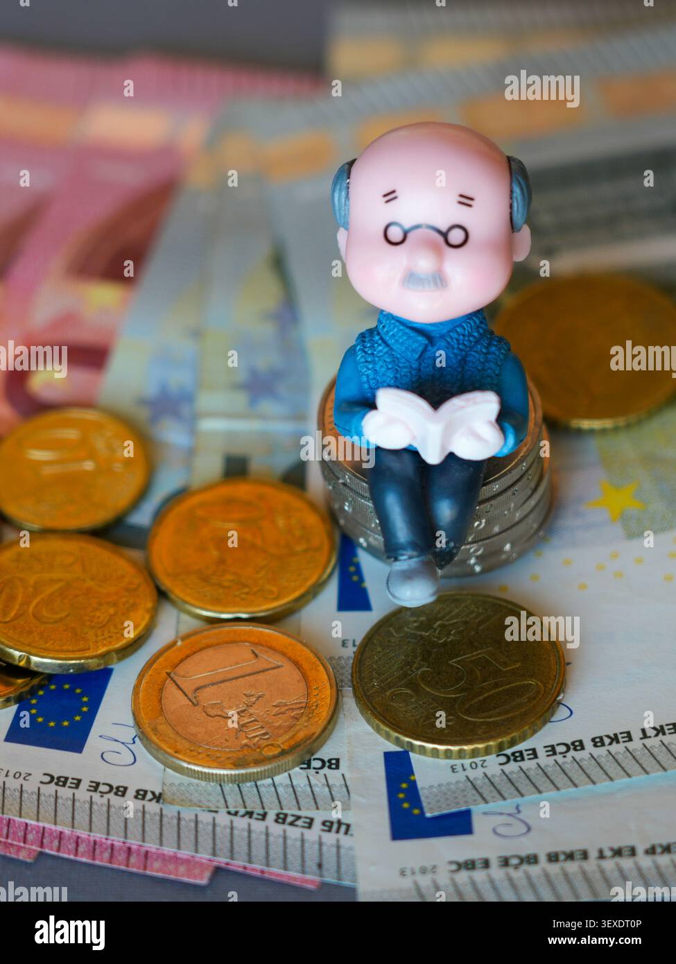Senior Figurine sulle monete in euro con banconote che illustrano oggi il risparmio pensionistico e il finanziamento pensionistico Foto Stock