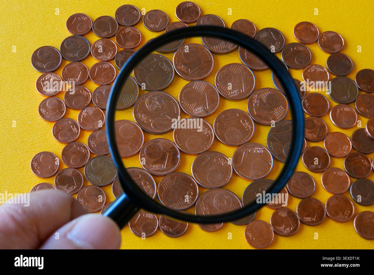 Lente d'ingrandimento che esamina le piccole monete in euro e il futuro della moneta di basso valore in Europa oggi Foto Stock