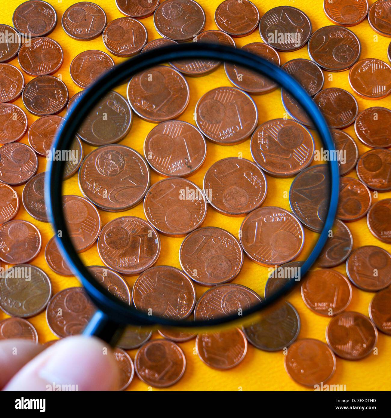 Lente di ingrandimento che esamina le piccole monete in euro e il loro futuro nelle transazioni in contanti quotidiane di oggi Foto Stock