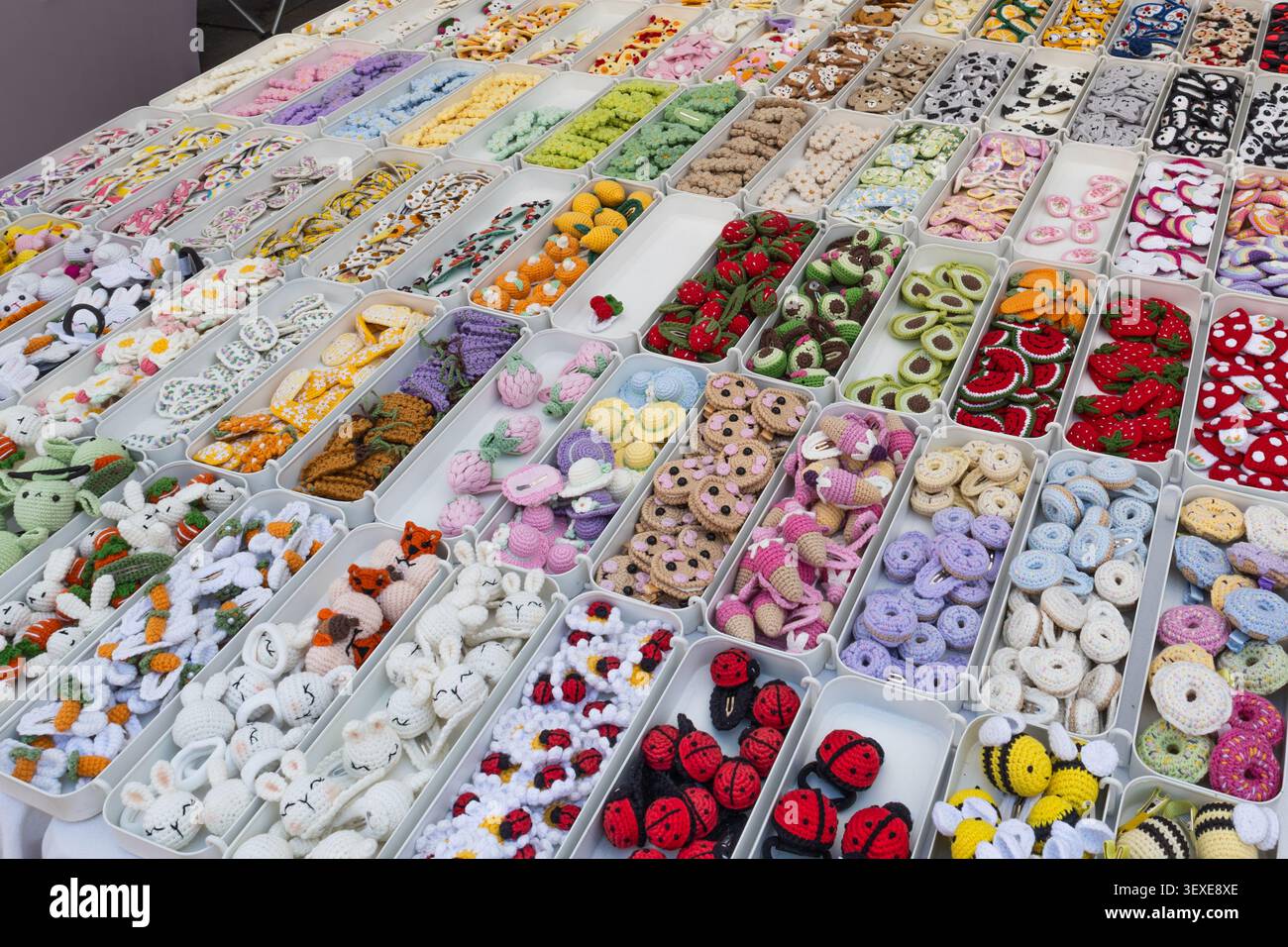 Collezione di piccoli bottoni fatti a mano e accessori artigianali esposti in un mercato di strada Foto Stock