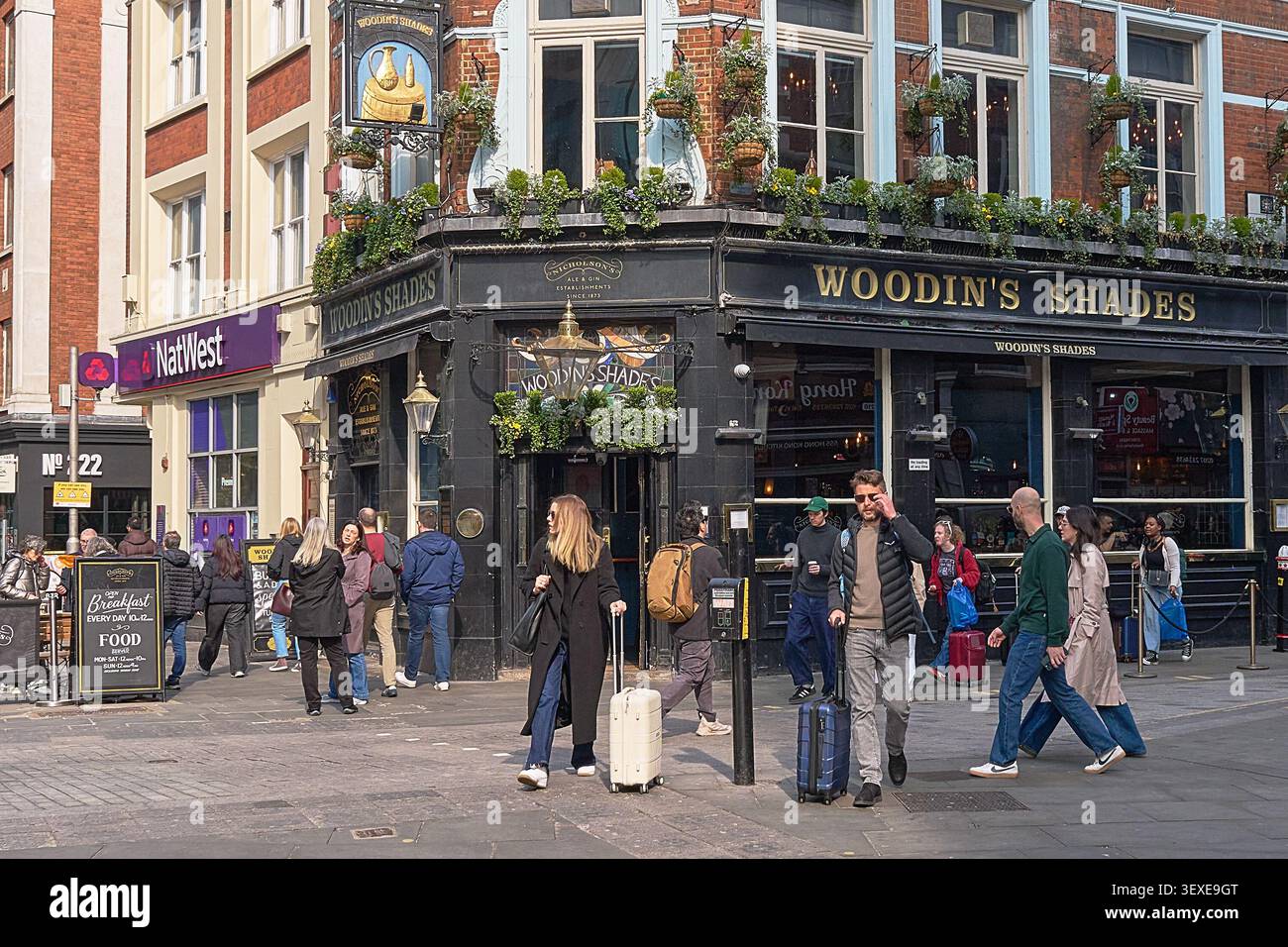 Vivace scena di strada al pub Woodin's Shades con gente che cammina, segnaletica e tradizionale architettura da pub nel centro di Londra. Foto Stock