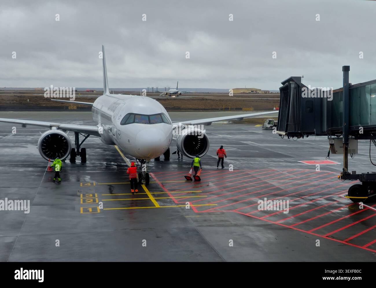 Vienna, Austria, 9 maggio 2026: Equipaggio di terra che prepara un aereo commerciale per l'imbarco presso un cancello dell'aeroporto, collegandosi a un ponte di jet in una giornata nuvolosa Foto Stock