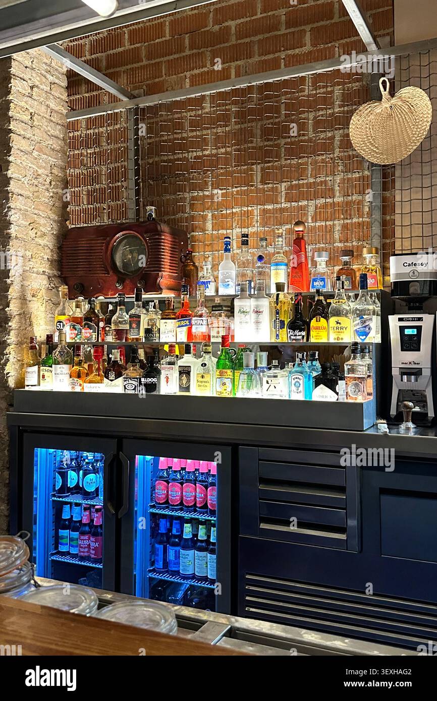 Interno di un moderno cocktail bar con scaffali illuminati, bottiglie di liquori, bancone bar e frigoriferi. Solo per uso editoriale. Valencia, Spagna - Augus Foto Stock