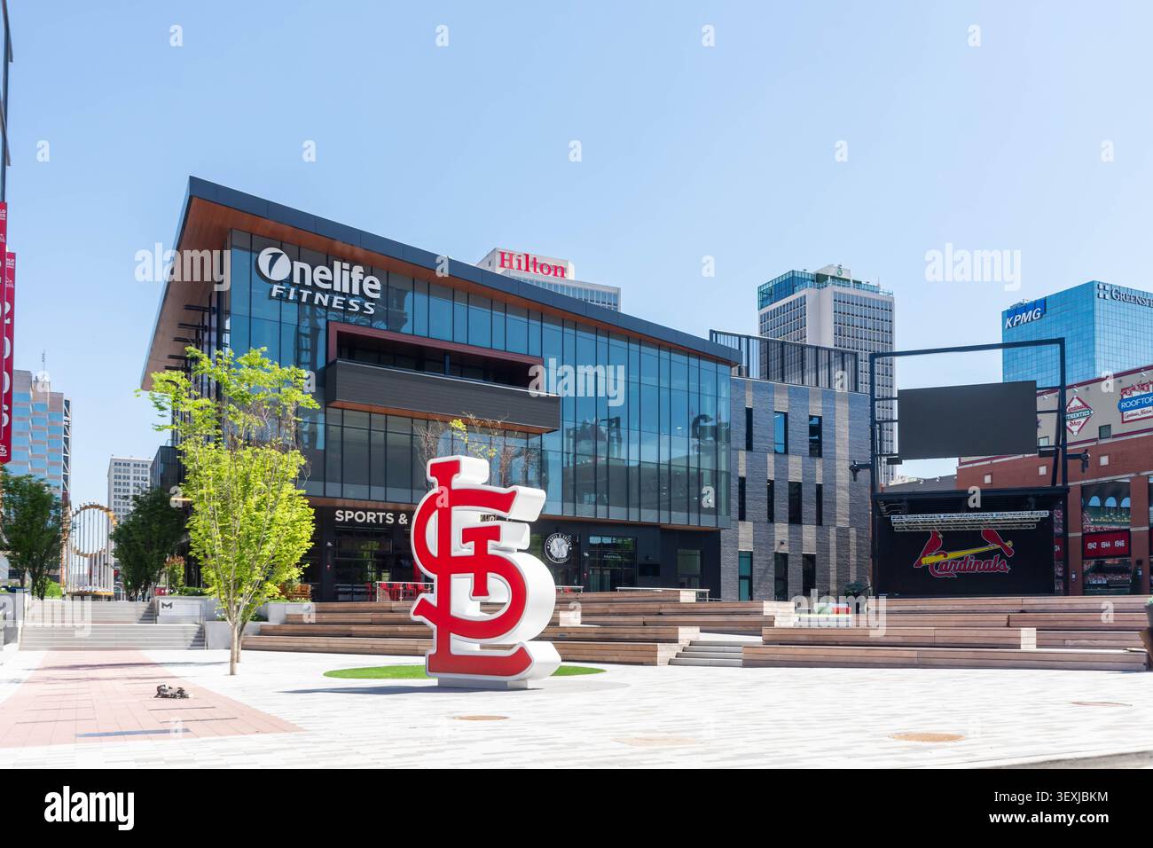 St. Louis, Stati Uniti - 25 giugno 2026: Vista del Ballpark Village con la scultura del logo dei St. Louis Cardinals, moderna architettura in vetro e cornice Foto Stock