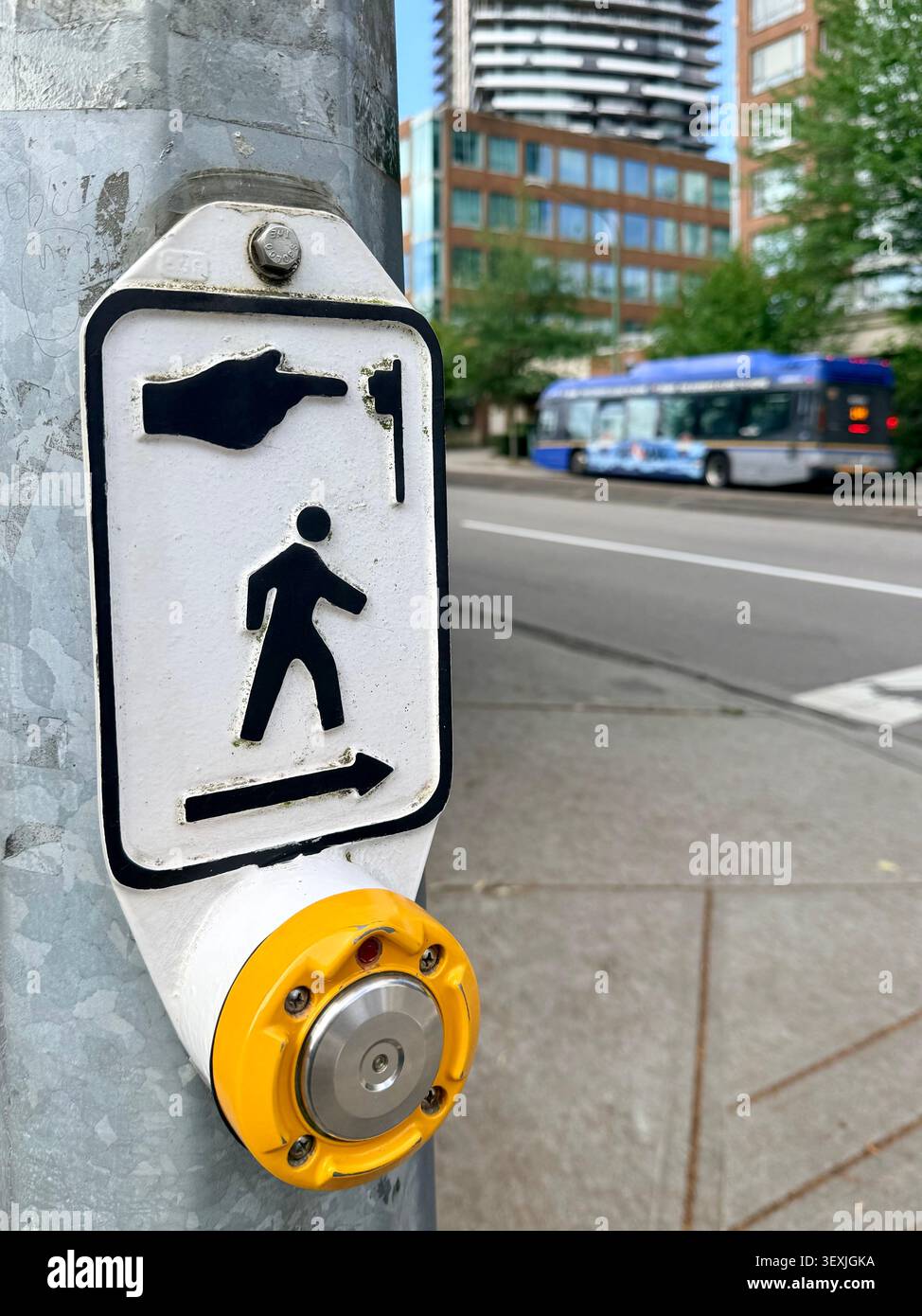 Pulsante per l'attraversamento pedonale e segnale del simbolo di camminata su una strada urbana trafficata a Vancouver, Canada. Foto Stock