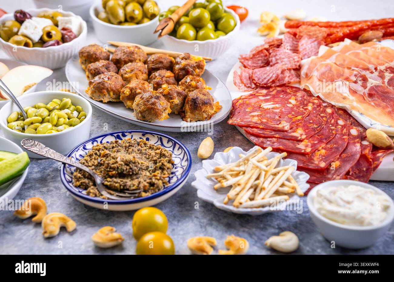 Un piatto ben organizzato con un assortimento di carni salate, olive salate, cremose e frutta fresca, perfetto per feste o picnic Foto Stock