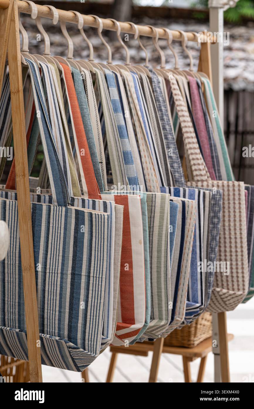 Borse tote colorate in cotone a righe con vari motivi appese su un rack di bambù in un mercato artigianale Foto Stock
