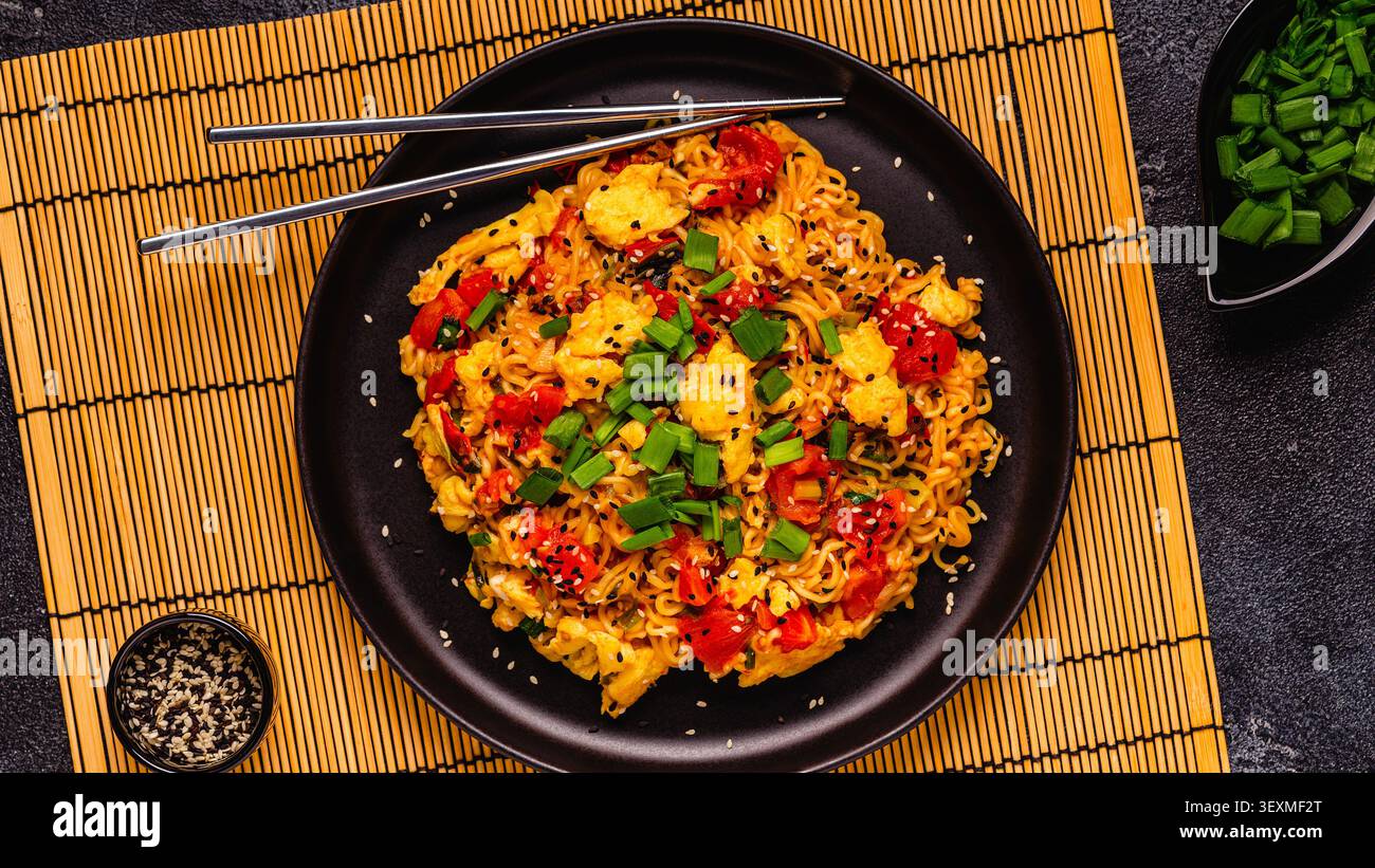 Spaghetti istantanei in stile coreano, Shin Ramyeon con pomodori e uova strapazzate, vista dall'alto. Foto Stock