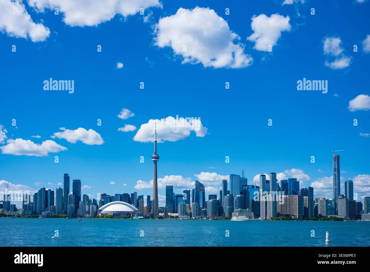 Lo skyline di Toronto si vede dall'isola di Toronto dall'altro lato del porto interno durante una giornata estiva con le nuvole di cumulus nel cielo. Foto Stock