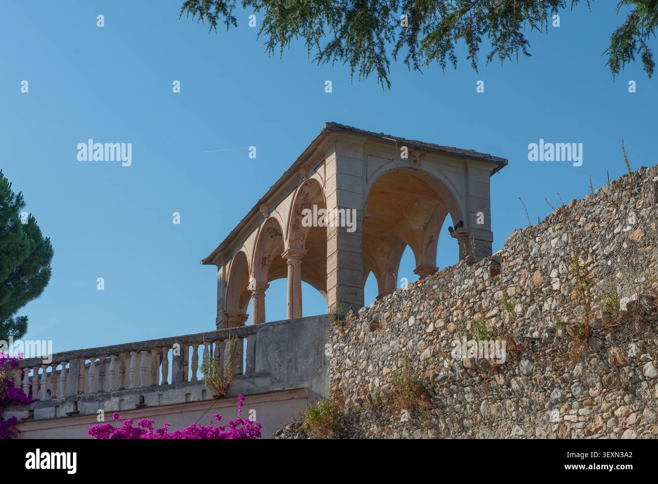 Un'antica loggia con archi e colonne si erge maestosamente sopra un'imponente cinta muraria in pietra a Loano, Liguria. Foto Stock