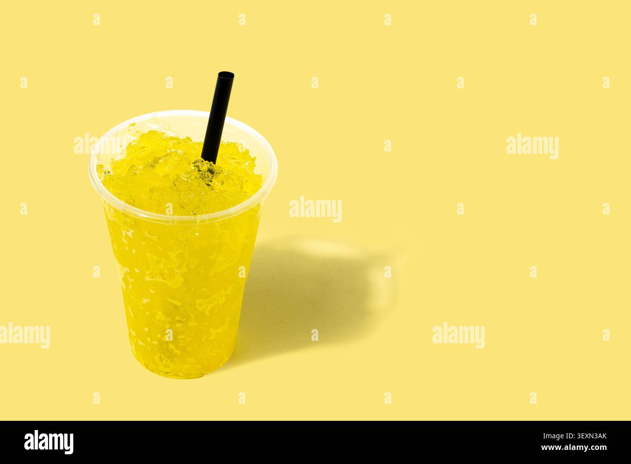 Bevanda gialla lushie in una tazza di plastica su sfondo giallo Foto Stock